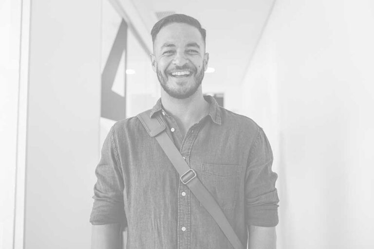 A man smiling for the camera in front of a wall.