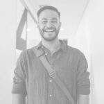 A man smiling for the camera in front of a wall.