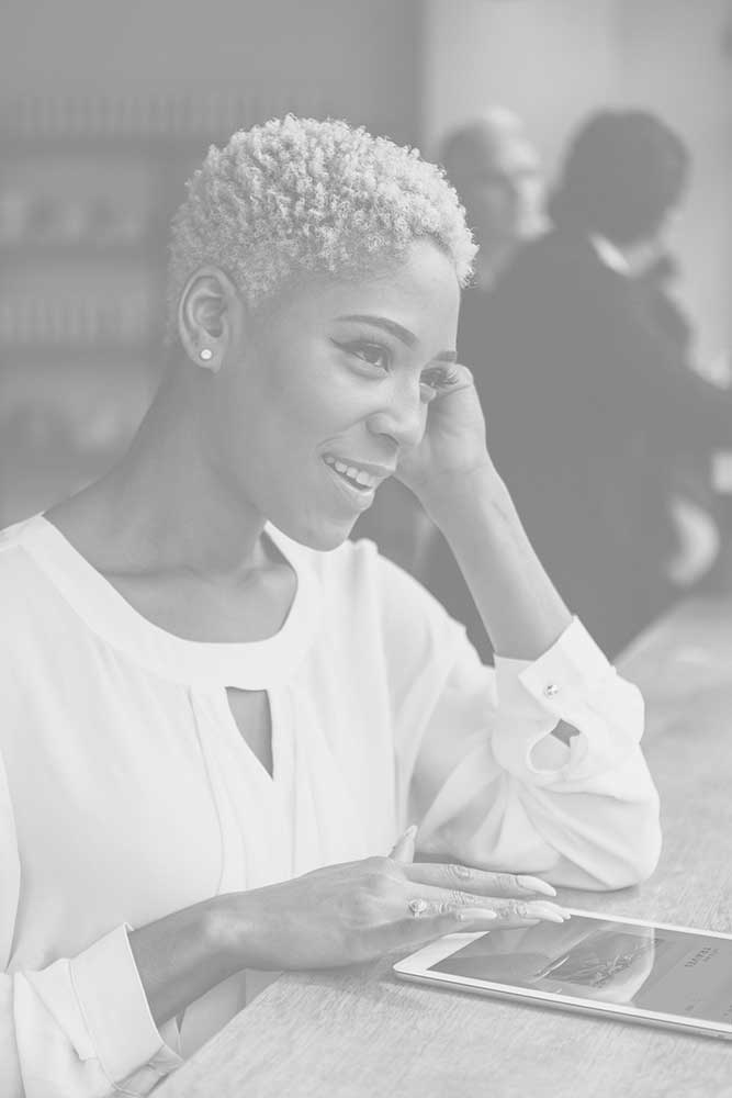 A woman with short hair is smiling and holding her phone.