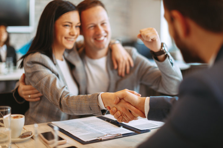 A man and woman shaking hands over paperwork.