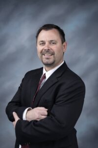 A man in a suit and tie standing with his arms crossed.
